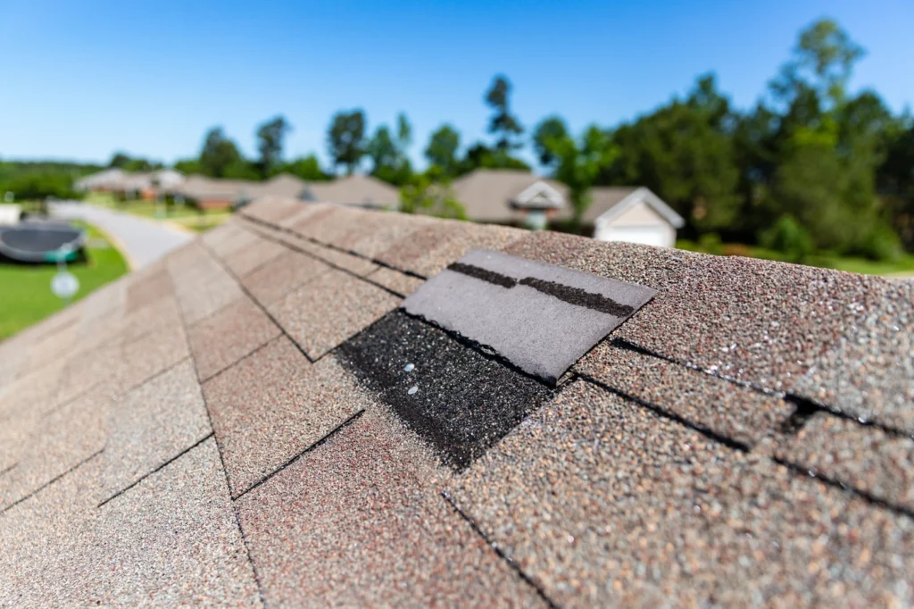 close up of shingle roofing system with missing shingles and hail damage roof
