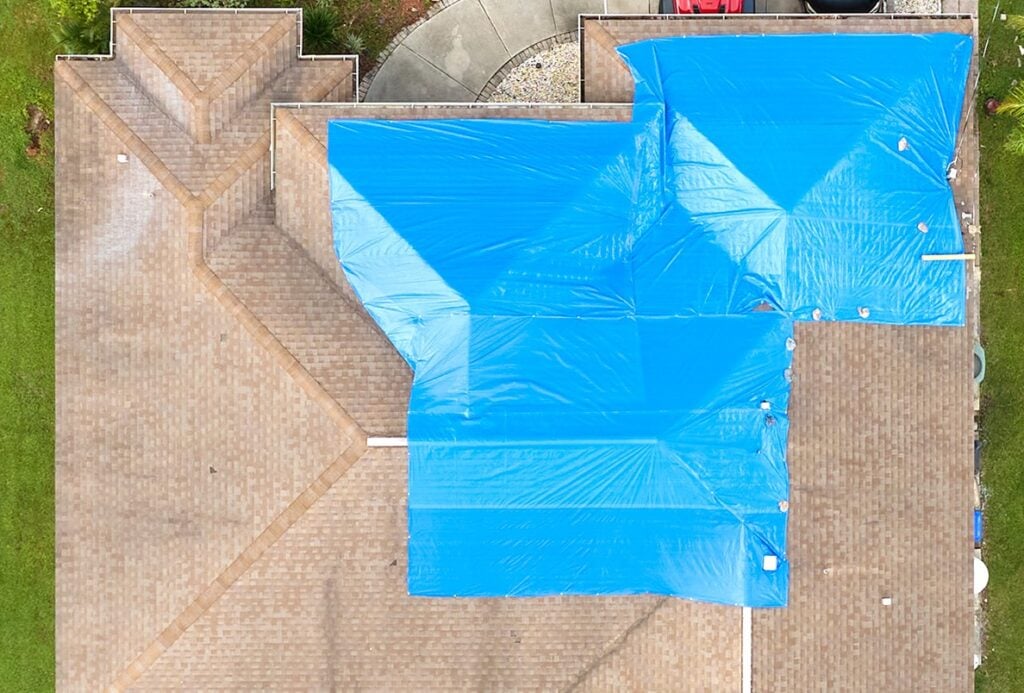 aerial view of a roof partially covered by a blue tarp