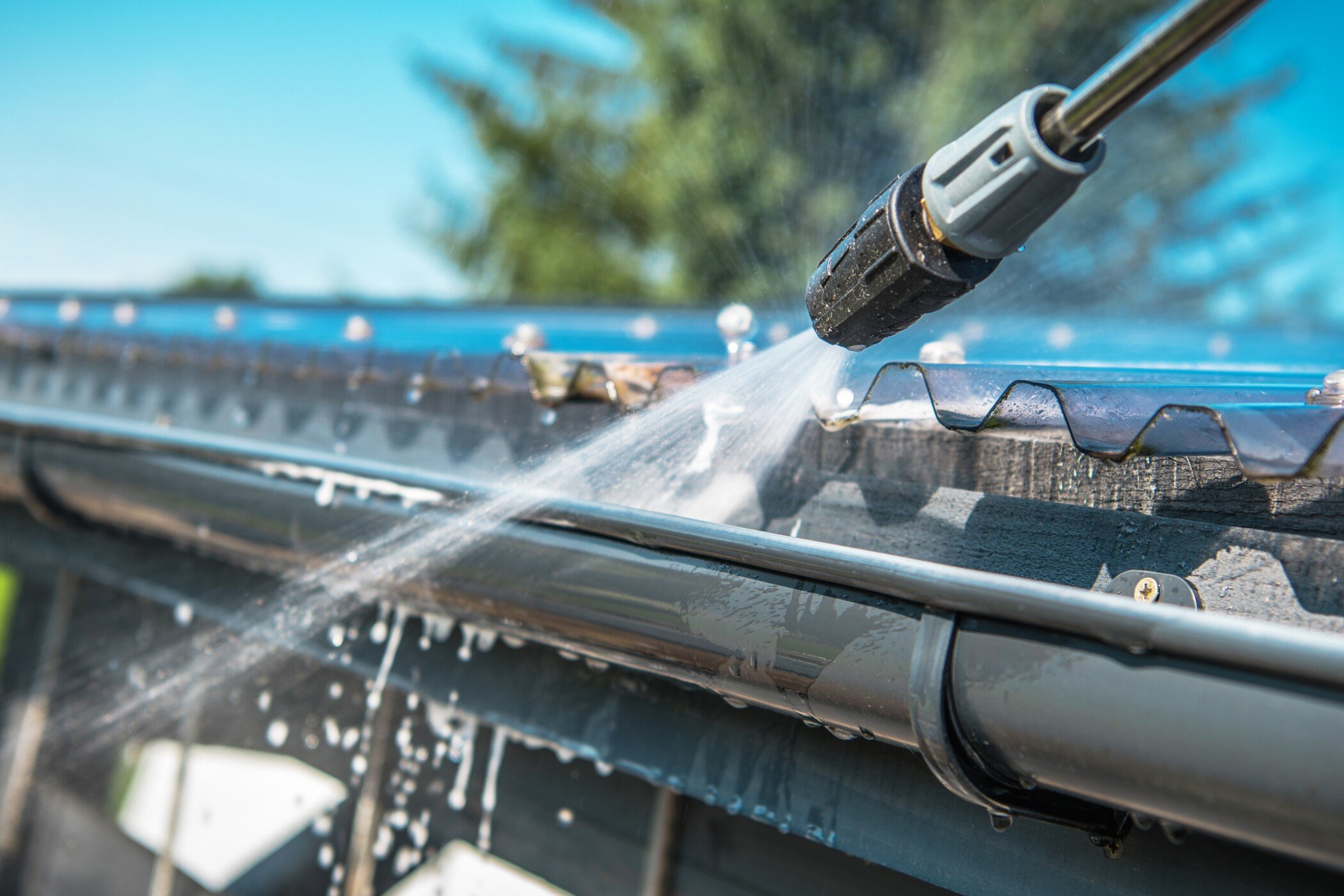 Closeup of pressure washing gutters and roof-gutter and roof cleaning