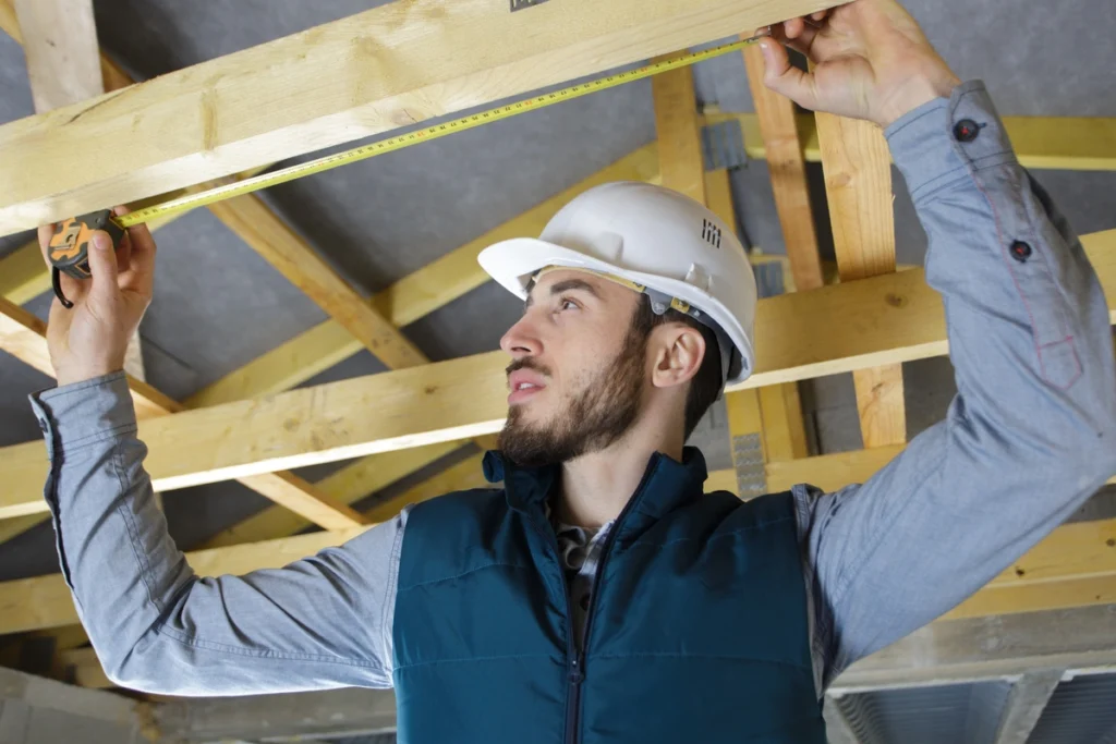 roofer measuring roof pitch with tape measure