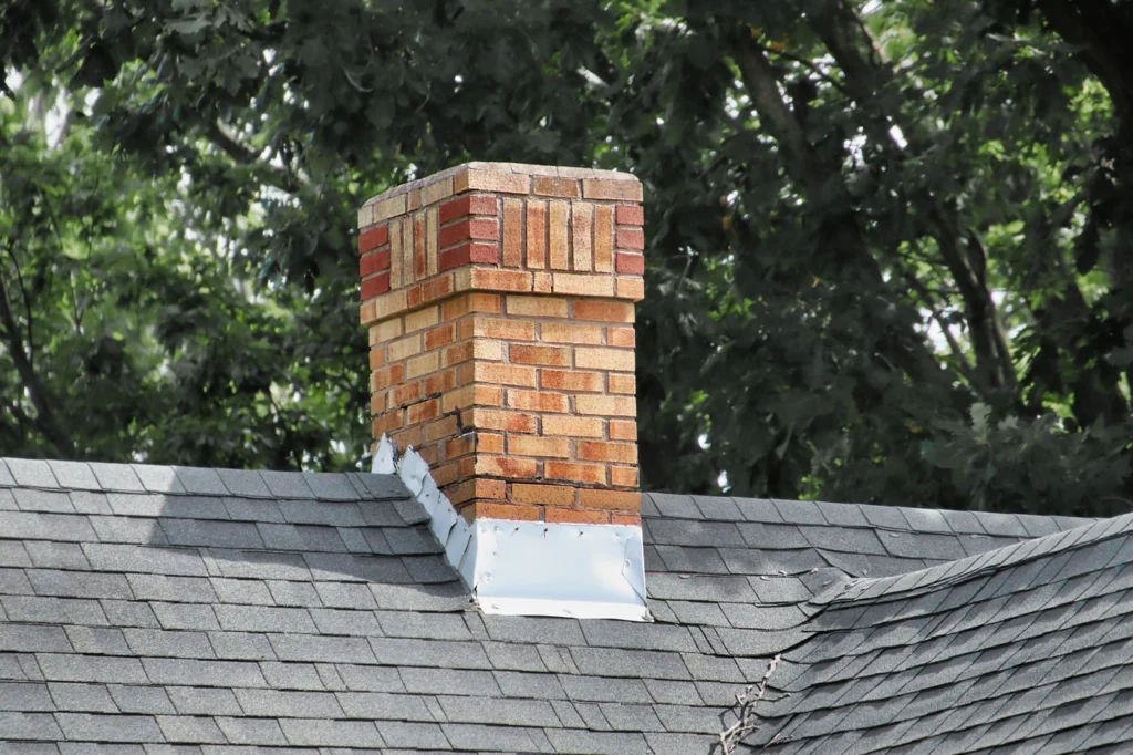Close up of gable roof with brick chimney and metal chimney roof flashing