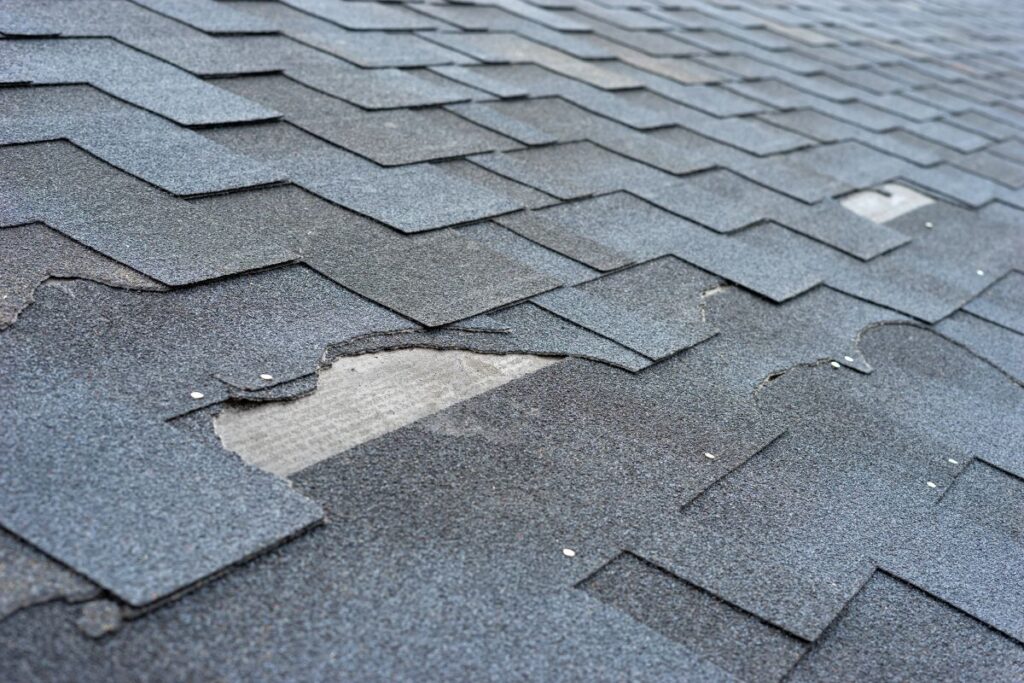 Сlose up view of asphalt shingles roof damage that needs repair
