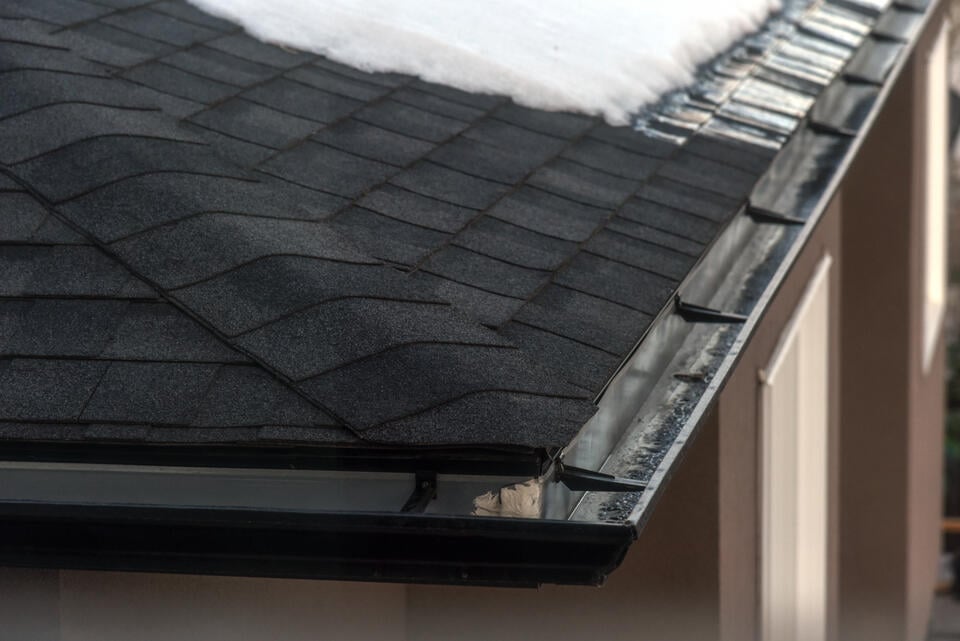 black roof shingles-close up of black shingles and the corner of a gutter system on a roof