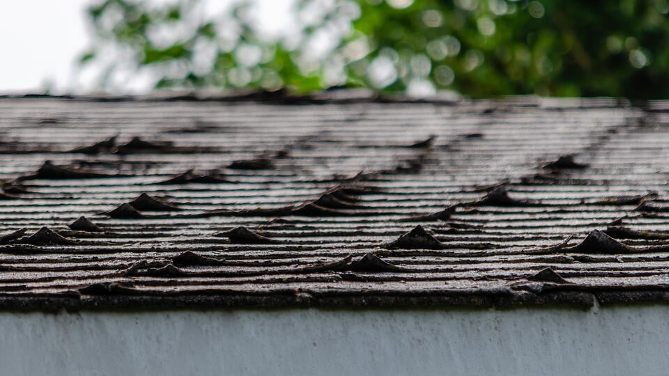 granule loss on shingles-close up view of curling shingles on house roof