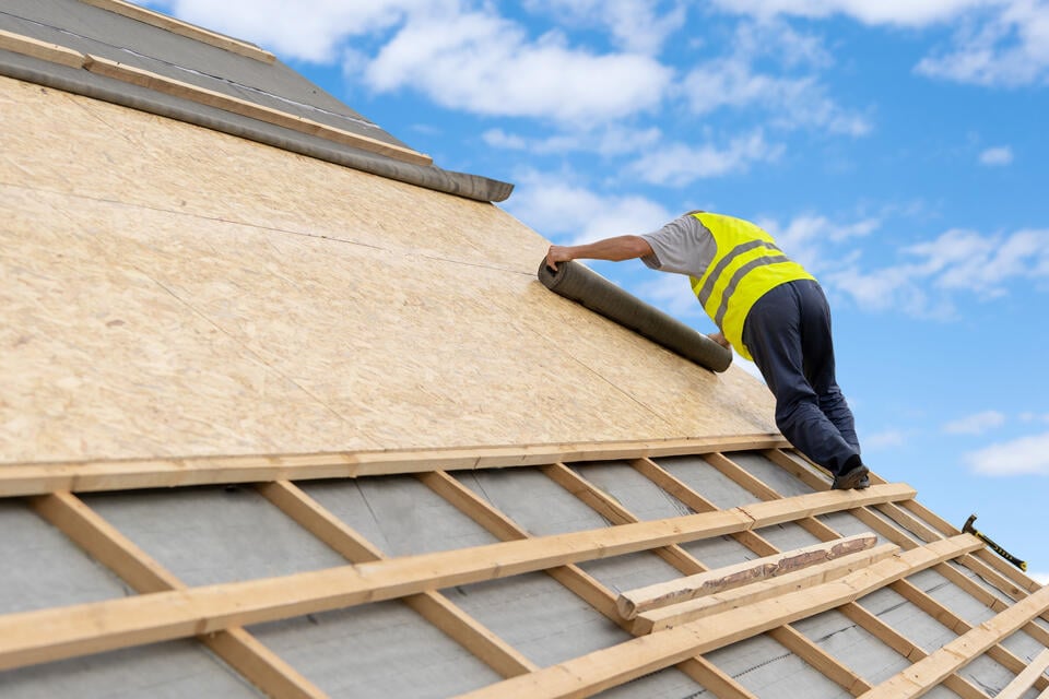 layers of a roof-roof decking and underlayment being installed