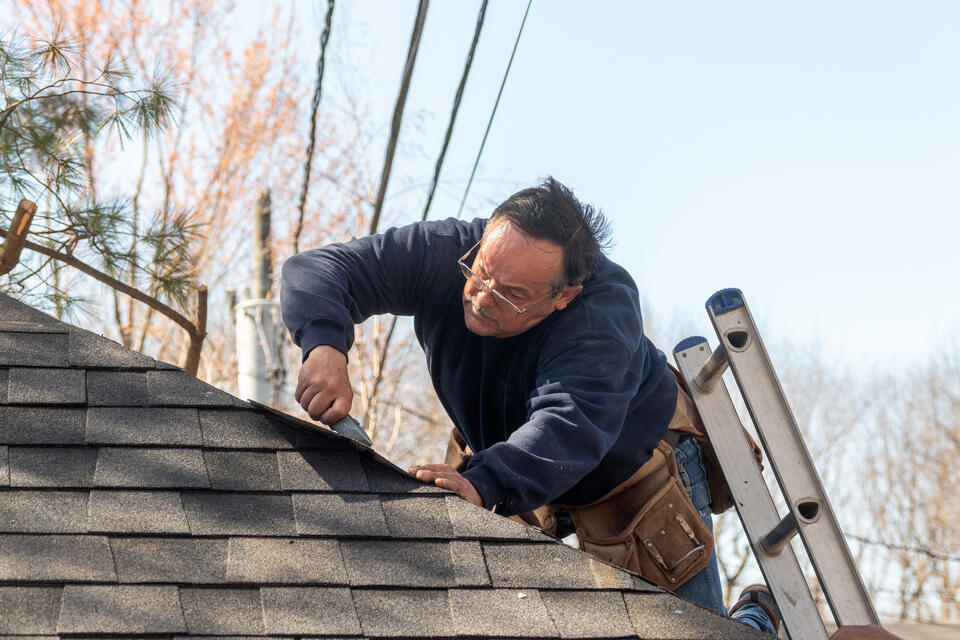 roof warranty-man on a ladder inspecting for roofing defects