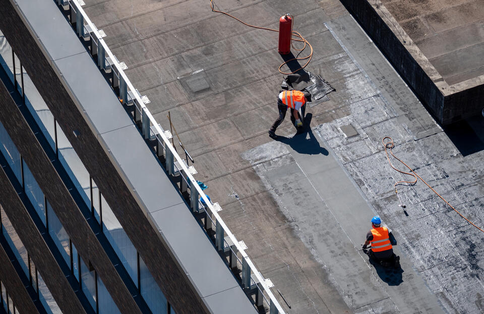 flat roof repair-aerial view of roof crew repairing commercial roof