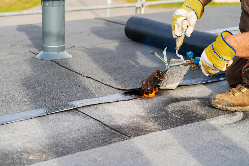 flat roof repair-close up of roofer repairing section of flat roof
