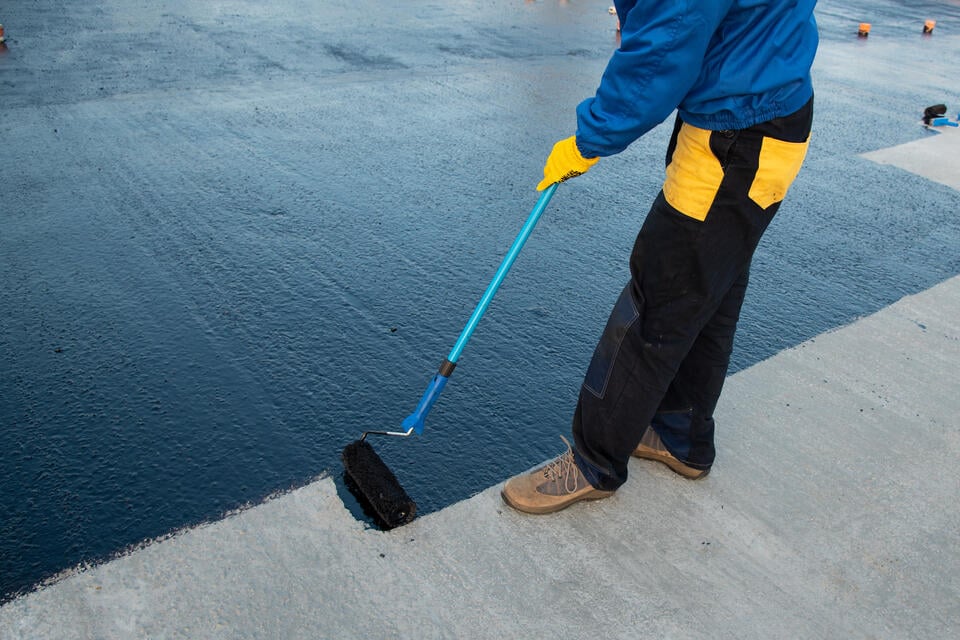 roof coating-close up of roofer painting on black roof coating