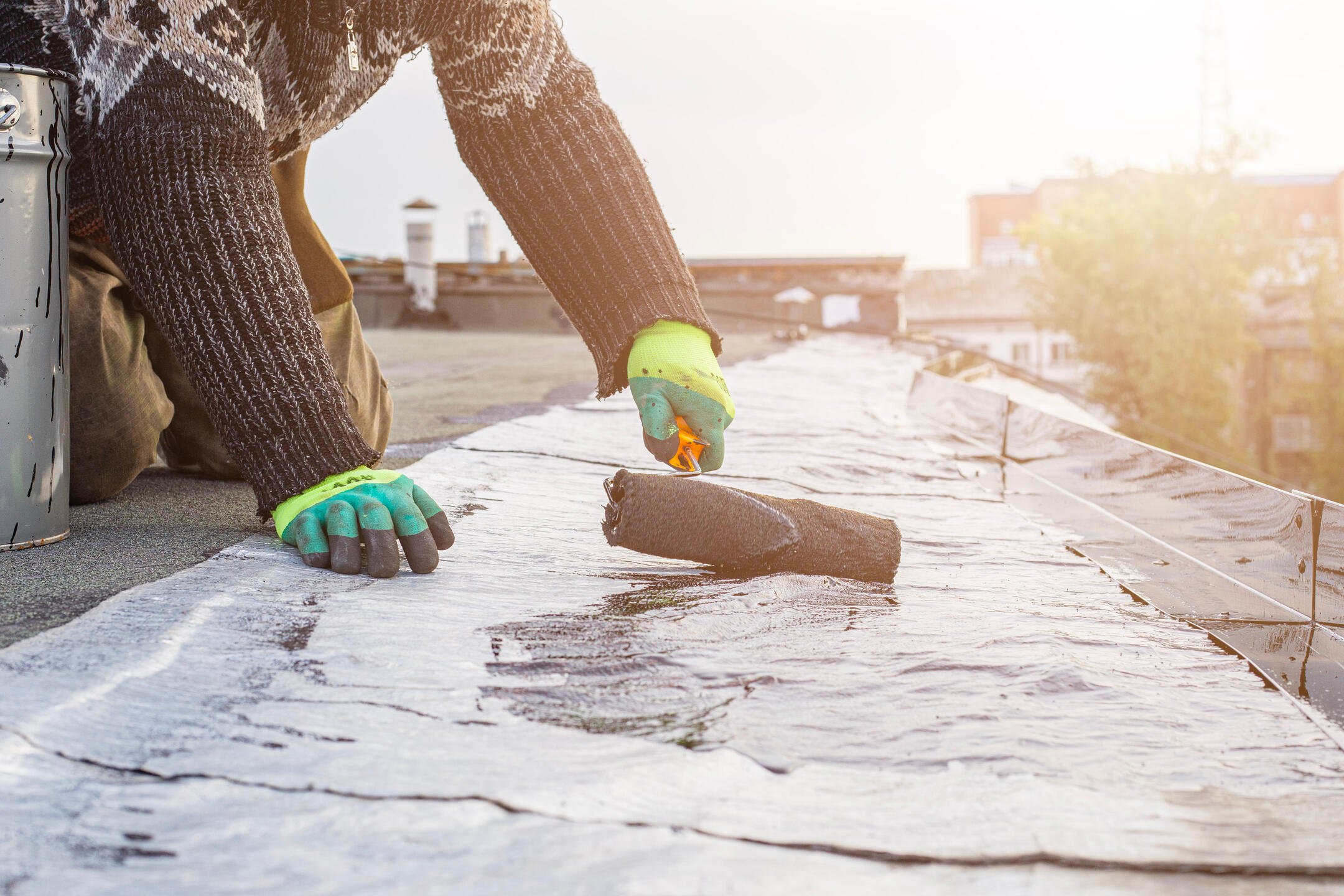 roof coating-close up of roofing rolling on roof coating with paint roller