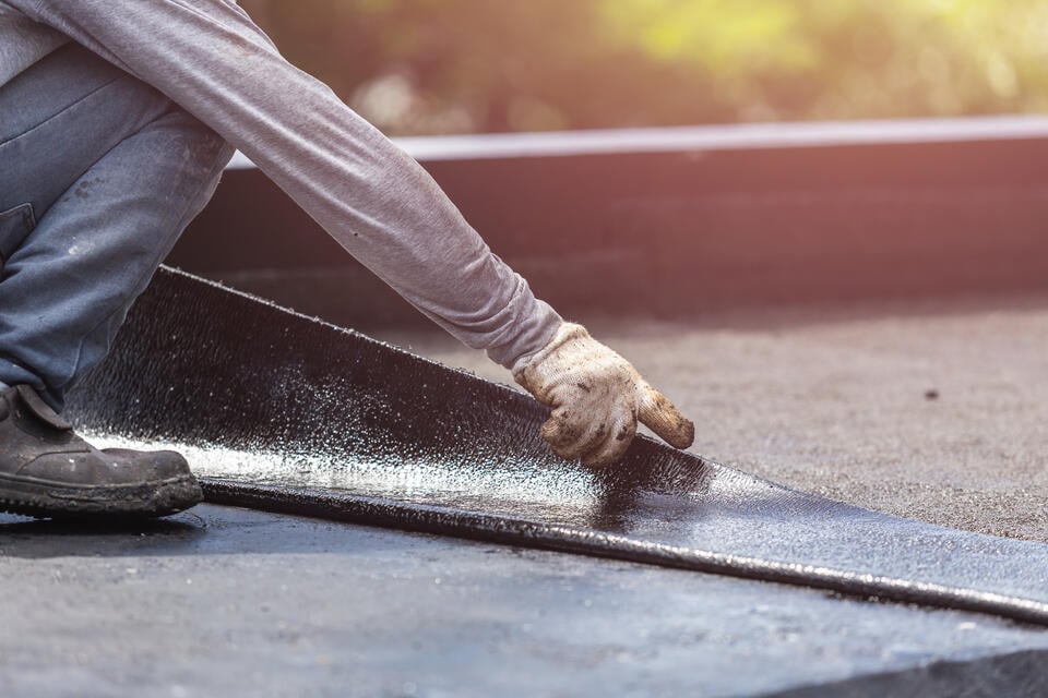 roof membrane-close up of man installing black roof membrane on flat roof