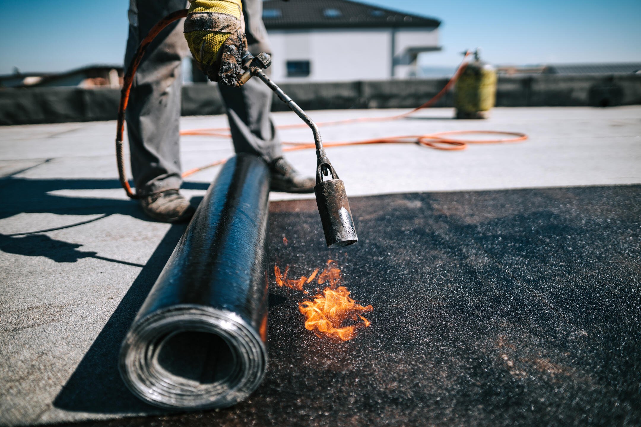 roof membrane-man in safety gear installing black roof membrane