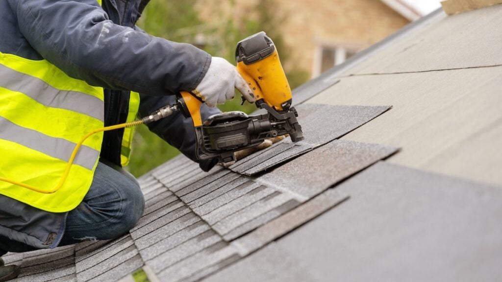person installing asphalt shingle roof
