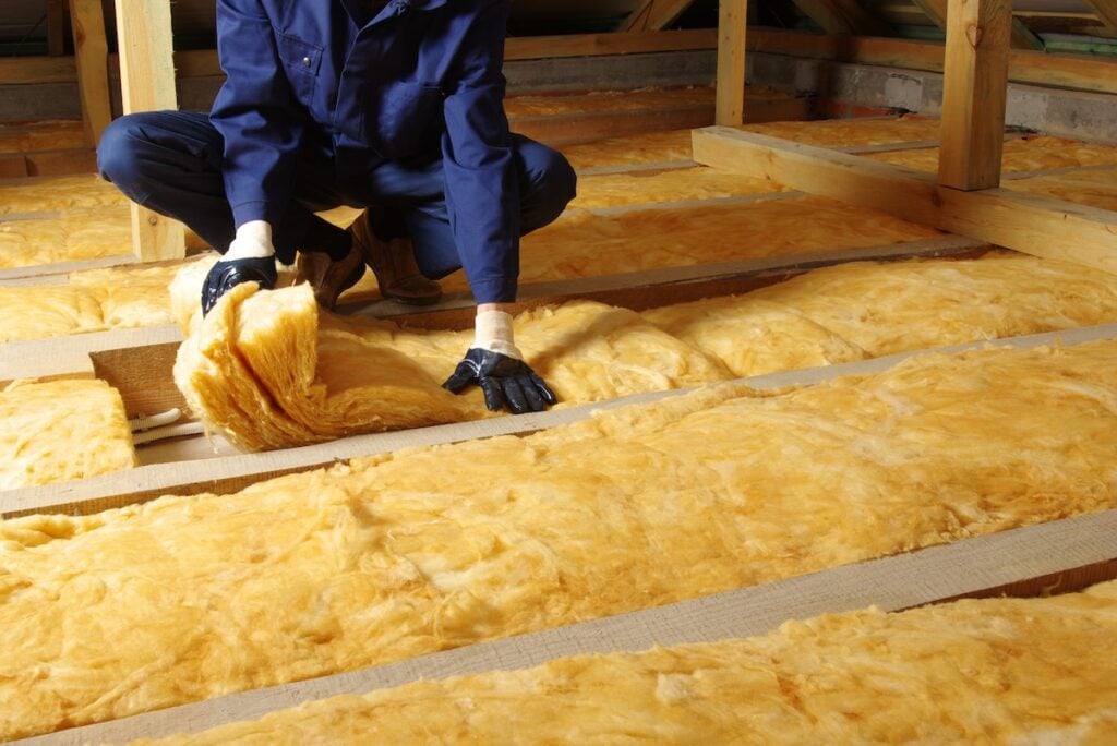 person installing insulation in roof interior
