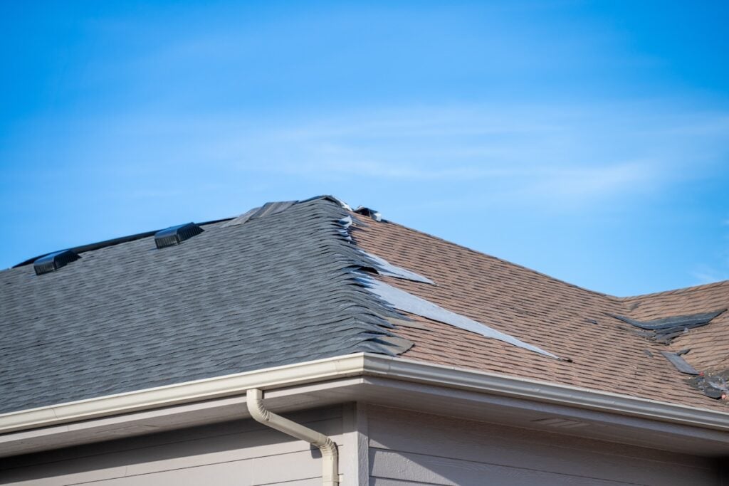 ground level view re-roofing overlay project at a residential house where new shingles are placed on top of existing tiles. . High quality photo