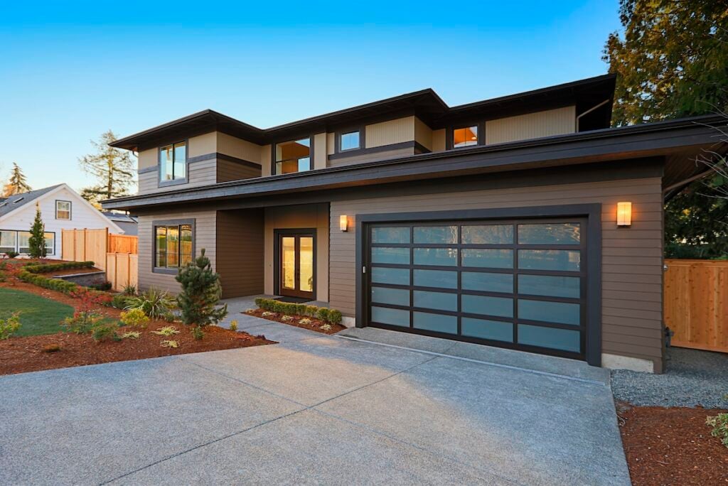 New construction home exterior with contemporary house plan features low slope roof, brown siding and glass garage door. Northwest, USA
