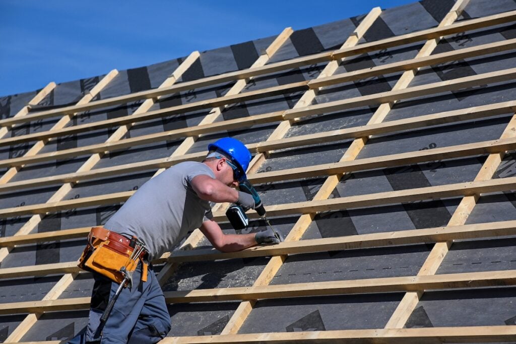 should i stay home during roof replacement Repair and replacement of the old roof with a new one. Construction worker in protective clothing standing on roof with tools.