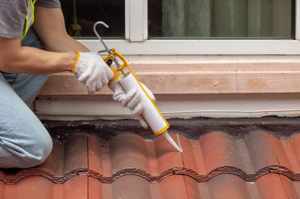 roof patch worket putting silicone coating orange tiles