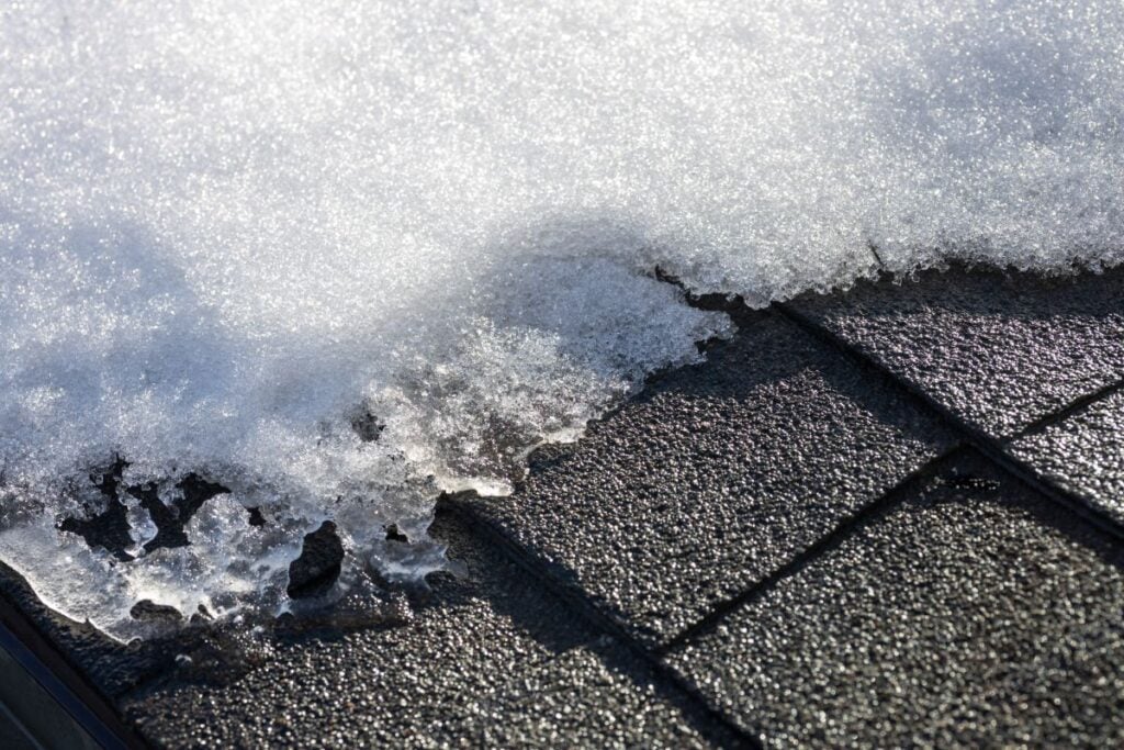 Full frame abstract texture background of snow beginning to melt on an asphalt shingled roof