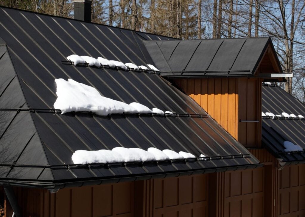 burnished slate metal roofing snow stuck on black metallic roof winter time