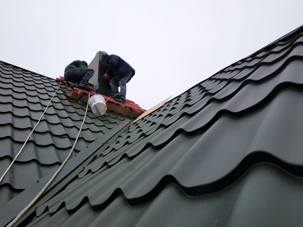 burnished slate metal roofing workers repairing back metallic roof