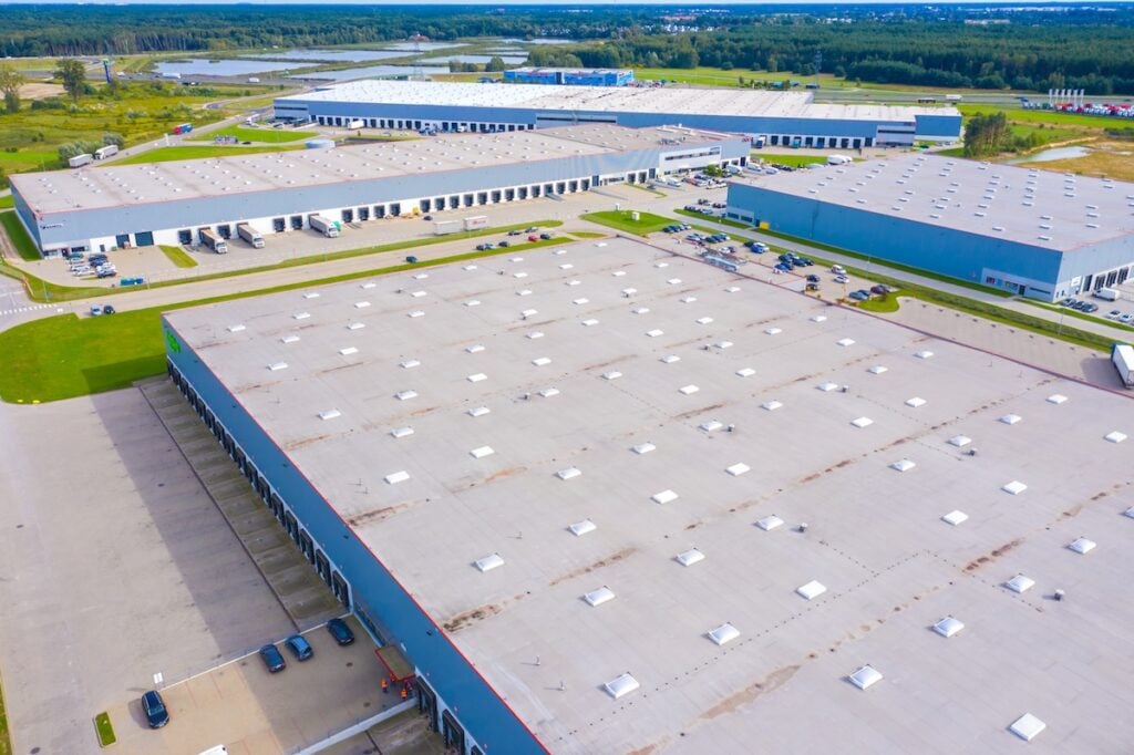 Aerial drone view of group of large modern industrial warehouse or factory buildings in suburban city area.Logistic transportation cargo terminal