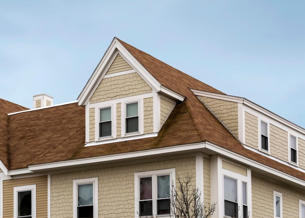 Dormer windows on the sloped shingle roof of a newly built house USA