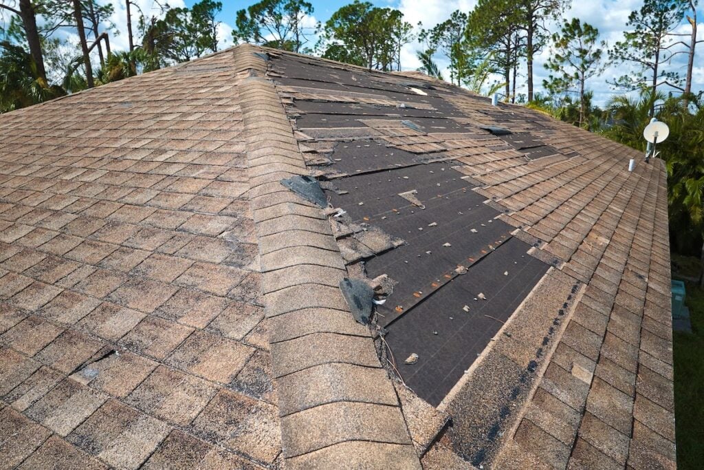Damaged house roof with missing shingles